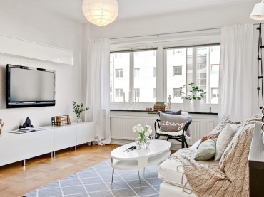 Białe szafki TV ,biały owalny stolik kawowy,białe zasłony i sofa w salonie,girlanda z żarówkami przy oknie w salonie (28485)