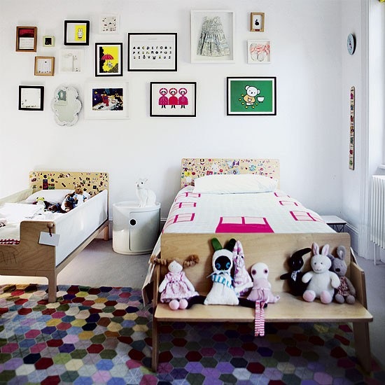 Drewniane łóżka i ławki, kolorowe dywany i kolorowe dekoracje w stylu boho w dziecięcym pokoju