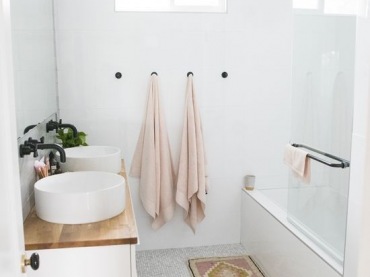 W niewielkiej łazience znajduje się kilka dekoracyjnych elementów. Jednym z nich jest mały dywanik ze wzorem przed wanną. Drewniany blat ładnie prezentuje się z bielą, co podkreśla inspirację skandynawskim...