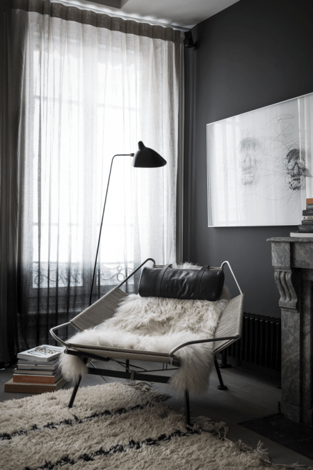 Czarne ściany,nowoczesna lampa podłogowa,metalowy fotel z siedziskiem z tkaniny