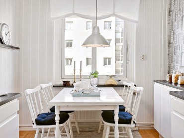 Biała roleta rzymska na oknie w kuchni,białe krzesła z drewena z siedziskami i biały prostokatny stół w stylu skandynawskim (28489)