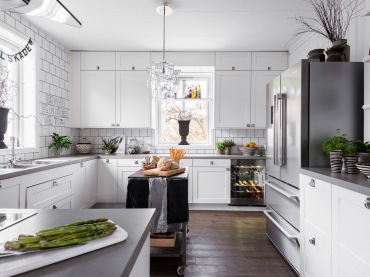 Białe kuchenne szafki rozświetlają przestronne wnętrze. Zabudowa od podłogi do sufitu na najkrótszej ścianie pozwala na wygodne przechowywanie wszystkich akcesoriów i...