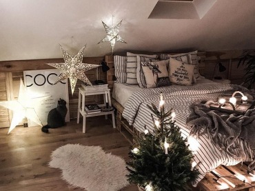 W sypialni na poddaszu znajduje się dużo dekoracji w klimacie świątecznym. Jest wśród nich podświetlana gwiazda, a także inne świetlne ozdoby, które razem z małą choinką zaznaczają świąteczny charakter...