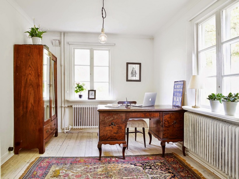 Żarówka na kablu,drewniana witryna,stylowe biurko na kabriolowych nóżkach i perski dywan na podłodze z naturalnego drewna