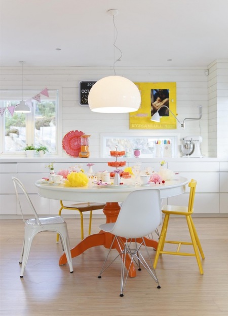 Okragły stół na pomarańczowej nodze,biało-pomarańczowy stół,drewniany stół z białym blatem,kolorowy stół okragły,stół okrągły z żółtym krzesłem,stół w białych wnętrzach skandynawskich