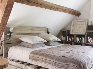 Łóżko z palety , regały z pólkami z drewnianych skrzynek w rustykalnej sypialni na poddaszu z belakami (25319)