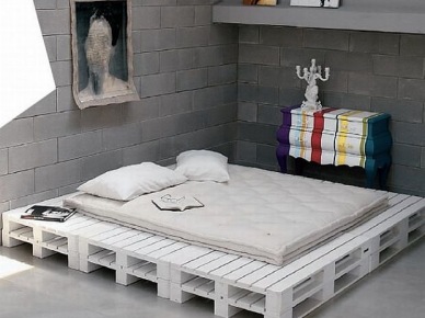 Podstawa i ramy łóżka z białych drewnianych palet w awangardowej sypialni z betonowymi scianami i kolorową komodą (25331)