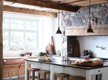 W aranżacji przestronnej kuchni uwzględniono zarówno drewno, jak i kamień. Podłoga i sufit z desek tworzą pewnego rodzaju ramy, w których zamyka się kuchenny...