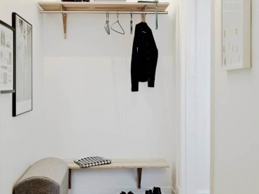 Drewniana podłoga i półki w małym przedpokoju,białe ściany,szara tapicerowana ławka,skandynawski biało-czarny dywanik (47831)