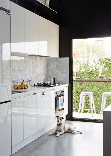 Panoramiczne  okno z drzwiami w białej kuchni z widokiem na ogród