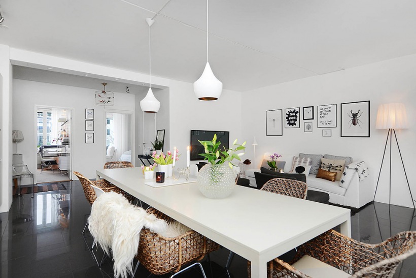 Piękna jadalnia z salonem z białym stołem, bambusowymi nowoczesnymi krzesłami w otawrtym widoku mieszkania