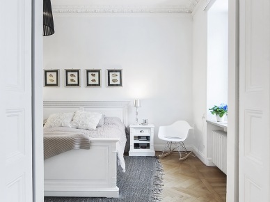 Białe łóżko z drewna,artprinty na ścianie i szary tkany dywan w skandynawskiej  sypialni (21986)