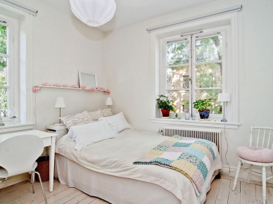 Biała sypialnia z patchworkowa narzuta w pastelach i różową girlandą na małej półce nad łóżkiem (24568)