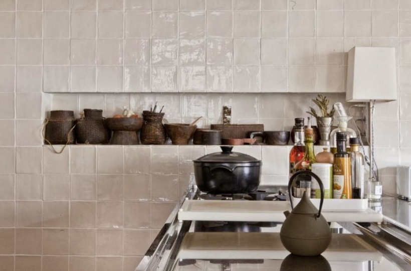 Oyginalna ściana z białych płytek z półką pełną dzbanków i naczyć w stylu vintage w aranżacji kuchni