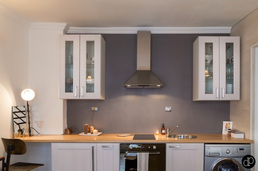 Szara ściana w kuchni,stalowy okap kuchenny,białe szafki kuchenne z drewnianym blatem w stylu skandynawskim
