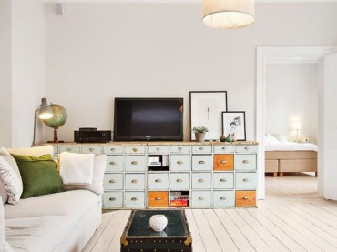 Turkusowo-miodowe szuflady w komodzie,skandynawskie grafiki,granatowy kufer stolik i biała sofa z zielonymi poduszkami (27739)