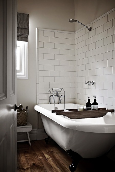 Brązowa podłoga z desek  w łazience ze stylową wanną na łapkach