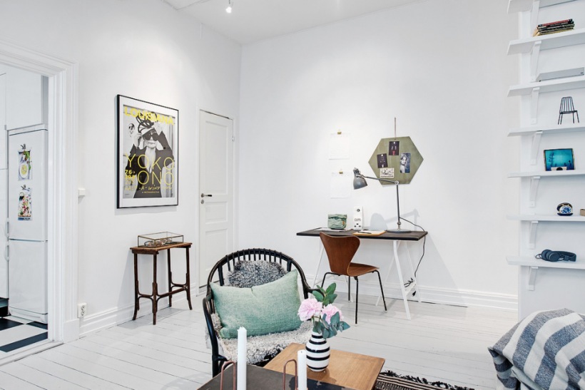 Biały salon skandynawski z małym biurkiem, czarnymi fotelikami z rattanu i turkusowymi dodatkami