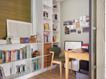 Mały pokój biurowy jest funkcjonalnie urządzony. Na dłuższej ścianie ustawiono białe regały, na których właściciele przechowują...