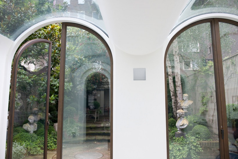 Świetki w łukowanym suficie i półokrągłe drzwi na taras z klasycznym ogrodem