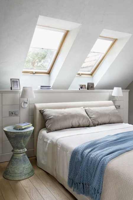 Aranżacja białej sypialni ze skośną ścianą z okanmi i tukusowymi dodatkami