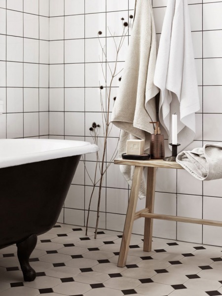 Czarna żeliwna wanna na łapkach,drewniana ławka,biała glazura w łazience w stylu skandynawskim