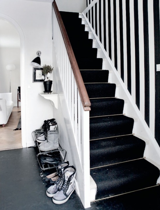 Czarne chodniki na schodach i tapeta w biało-czarne pasy na ścianie
