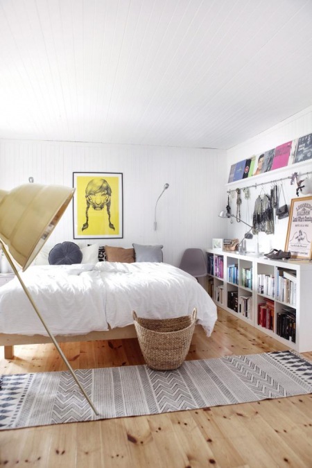 Niski regał z otwartymi pólkami i nowoczesne plakaty w aranżacji skandynawskiej sypialni