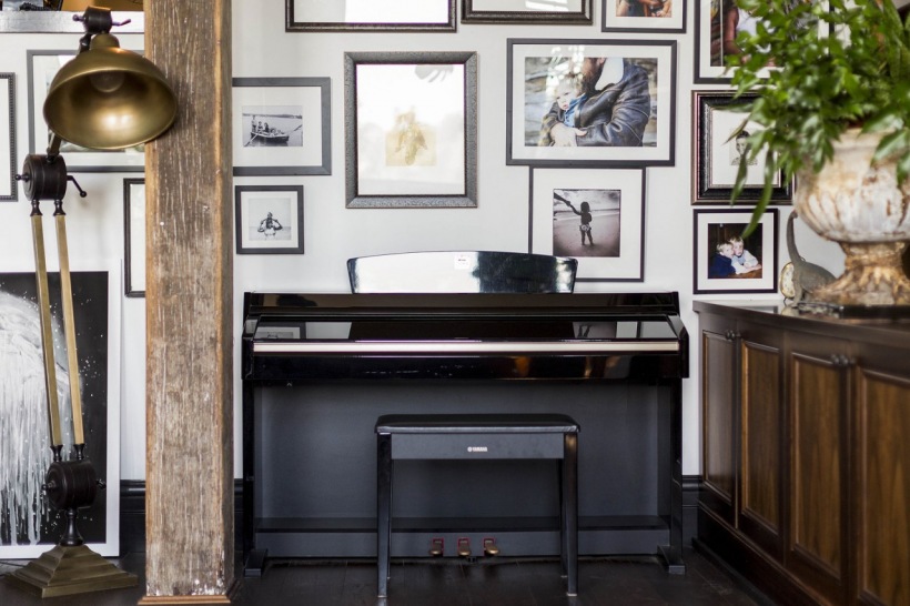 Czarne pianino przy ścianie z galerią w aranżacji salonu
