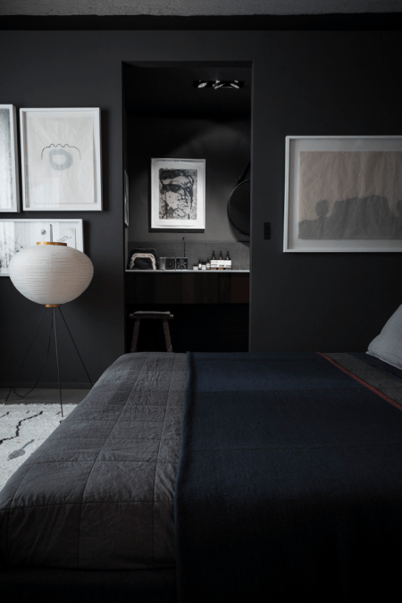 Aranżacja nowoczesnej sypialni w czarnym kolorze z białymi grafikami na ścianie