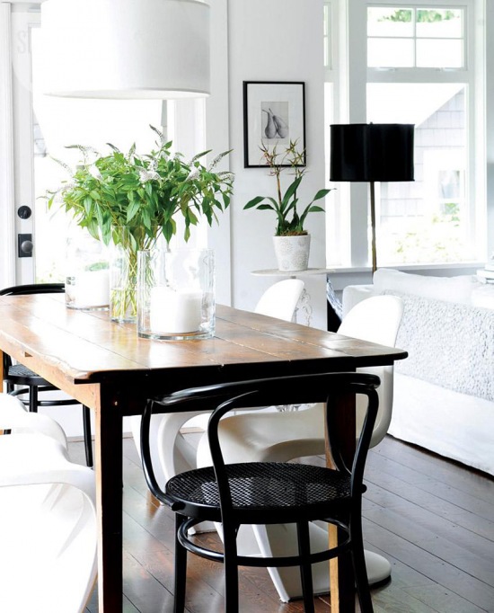 Czarne krzesło z gietego drewna,rustykalny drewniany stół,nowoczesne białe i czarne lampy oraz krzesła panton w jadalni
