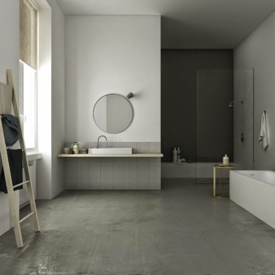 Minimalistyczna aranżacja łazienki z betonową posadzką,drabiną wieszakiem,okragłym lustrem i złotym stolikiem pomocniczym