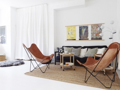 Beżowy dywan,czarno-białe poduszki,czarna sofa,brązowe fotele butterfly i drewniany stolik w aranżacji salonu z białą podłoga i ścianami (24653)