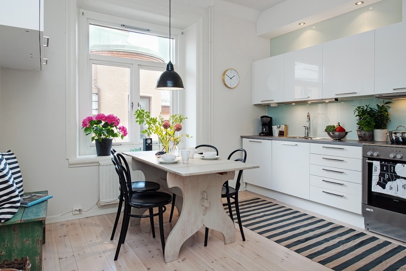 Biała minimalistyczna kuchnia skandynawska z rustykalnym stołem,czarnymi krzeslami z giętego drewna, i dywanem w biało-czarne paski