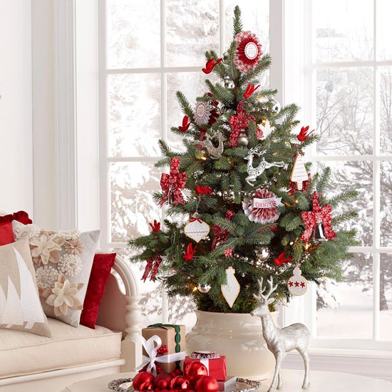 Biało-czerwone dekoracje świąteczne i mała choinka w ceramicznym wazonie na stole