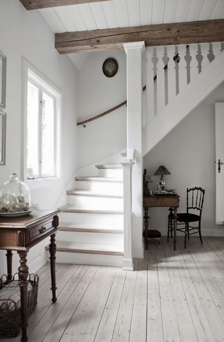 Białe drewniane schody dywanowe w domu z drewnianymi belkami