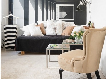 Karmelowy fotel uszak i karmelowe poduszki na czarnej sofie w salonie z czarno-białą fototapetą na ścianie (26260)