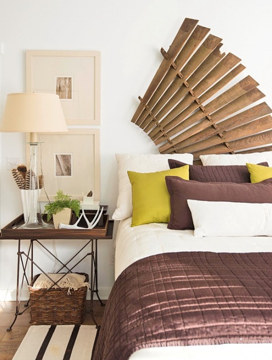 Dekoracja ścienna wachlarz z bambusa, metalowy stolik z drewnianą tacą,wiklinowy kosz i białe łóżko ubrane w brązowo - oliwkowe narzuty i poduszki