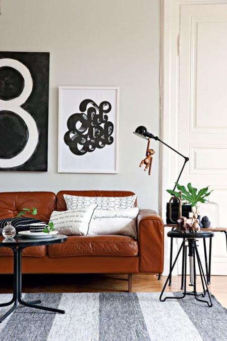Skórzana sofa brązowa, czarna lampka i stoliki w skandynawskim salonie