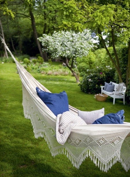 Romantyczny hamak z niebieskimi poduszkami w zielonym ogrodzie