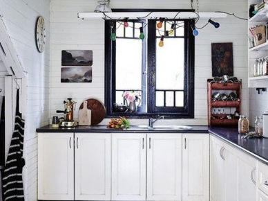 Czarny ornament na białej podłodze w kuchni,białe szafki,czarne okno i dodatki i kolorowa girlanda z żarówkami nad oknem kuchennym (26601)
