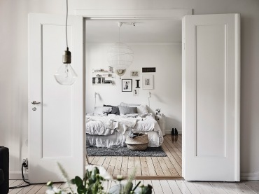 Bielone deski na podłodze,nowoczesne grafiki na białej ścianie i białe drewniane dwuskrzydłowe drzwi w sypialni (47740)