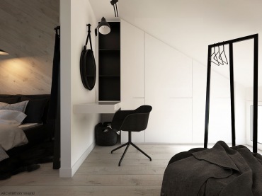 Sypialnia, mimo że ulokowana na poddaszu, jest dostatecznie wysoka, a tam, gdzie zaczyna się skos, przygotowano komfortową garderobę. Biały blat przymocowany do ściany i czarne krzesełko, lustro oraz lampa wyznaczają...