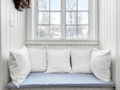 Pomysłowe  siedzisko z białych desek i poduszek pod małym oknem (21961)