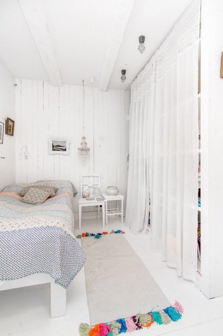 Mała sypialnia w białym kolorze z dywanikiem z kolorowymi pomponami