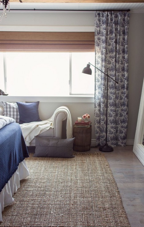 Beżowy tkany dywan w sypialni fajnie nawiązuje do drewnianych ścian. Duże białe lustro oparte o ścianę optycznie...