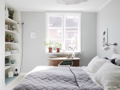 Szaro-liliowa narzuta pikowana na łóżku w sypialni z wnęką ścienną z półkami,drewniane biurko pod oknem (26528)
