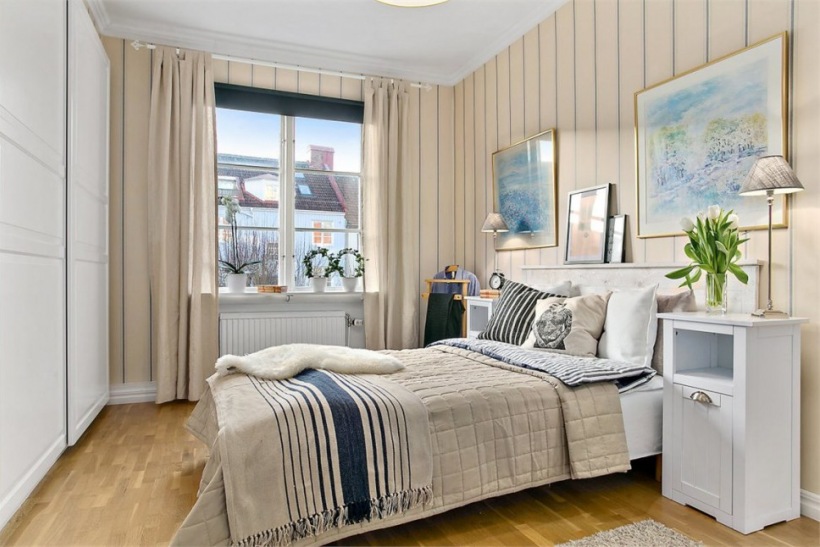Biało-beżowa sypialnia skandynawska z granatowymi dodatkami na łóżku