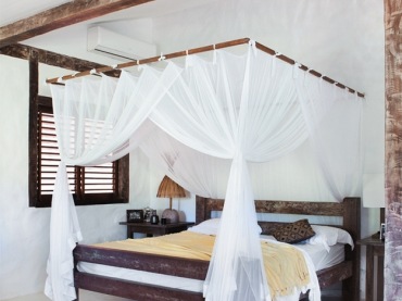 Drewniane łóżko z białymi zasłonami w sypialni (18007)