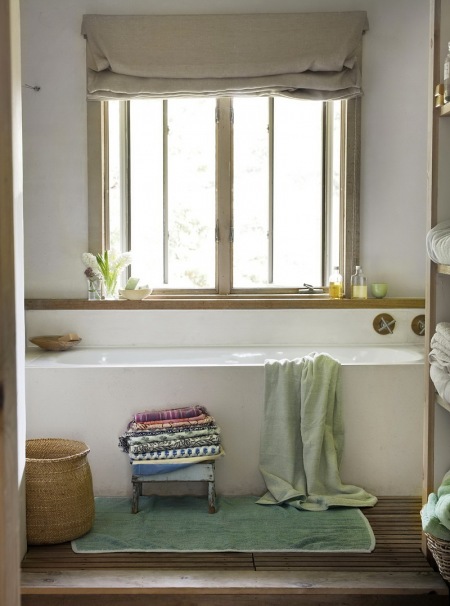 Szaro-beżowa roleta rzymska na oknie w prostej łazience z białymi i drewnianymi detalami